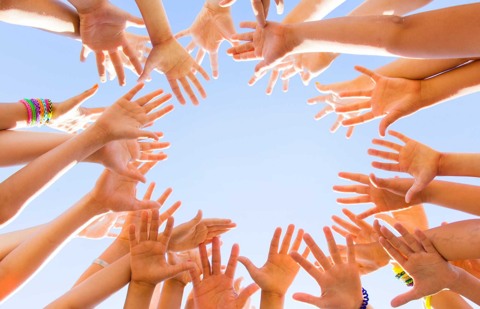Children's hands reach for the sky forming a circle